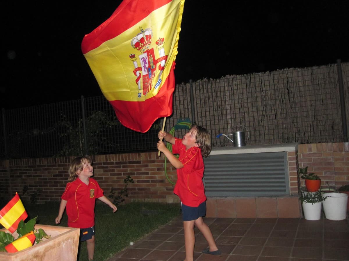 Marcos y Gonzalo de pequeños ondeando la bandera de España de noche