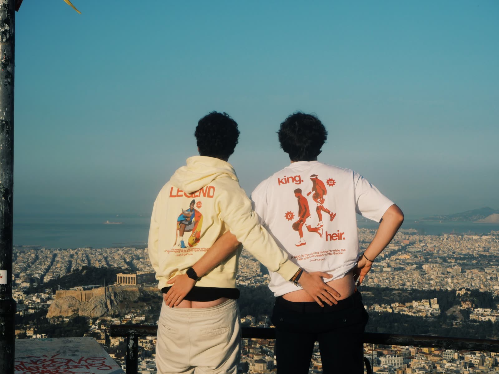 Modelos con King Heir Tee y sudadera Legend de Santofimia frente a la Acrópolis de Atenas